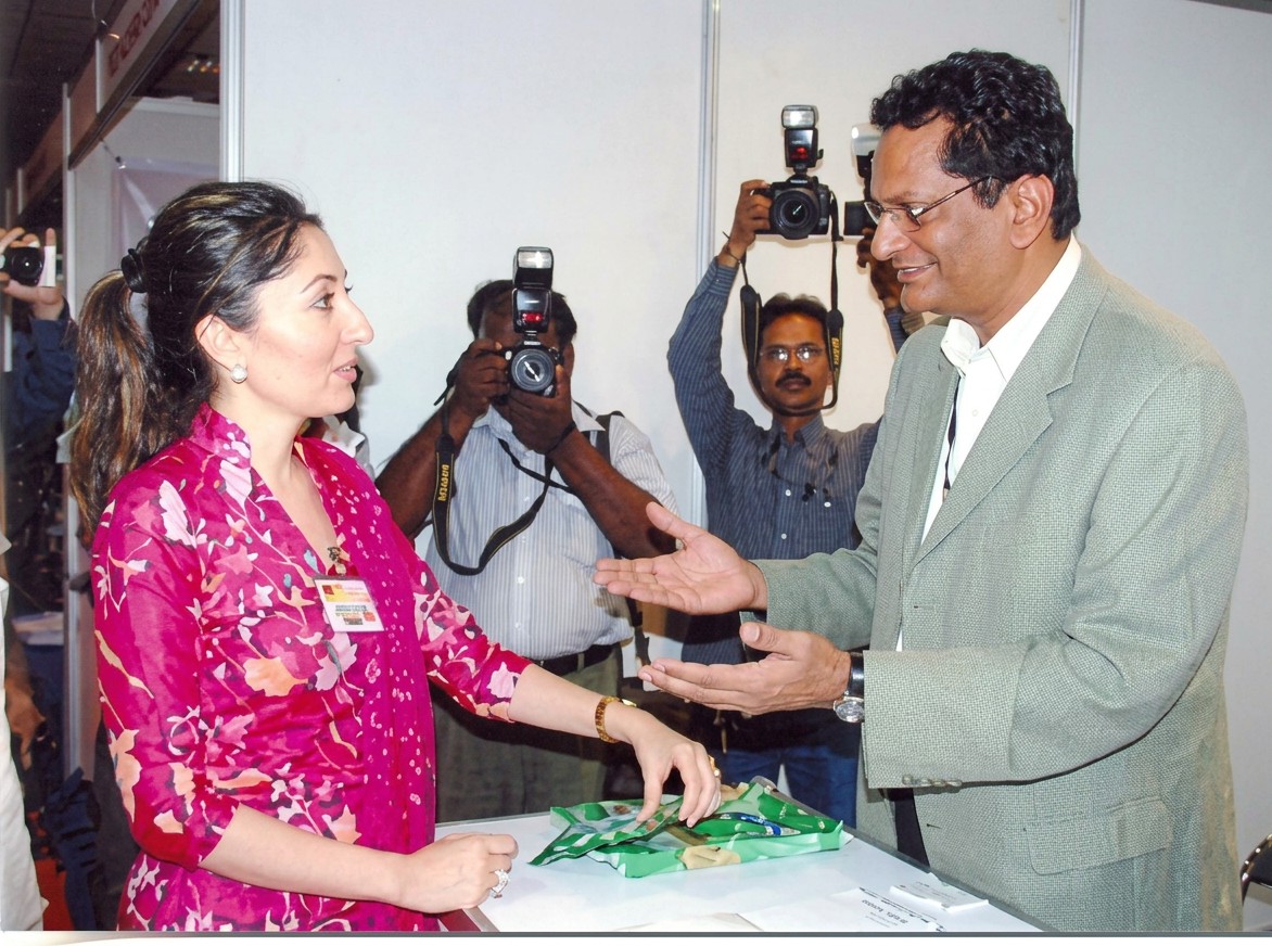 WTAP delegate greeting an exhibitor at a trade fair as photographers record the moment